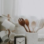 Home A minimalist kitchen scene featuring utensils, mugs, and a clock on the counter.